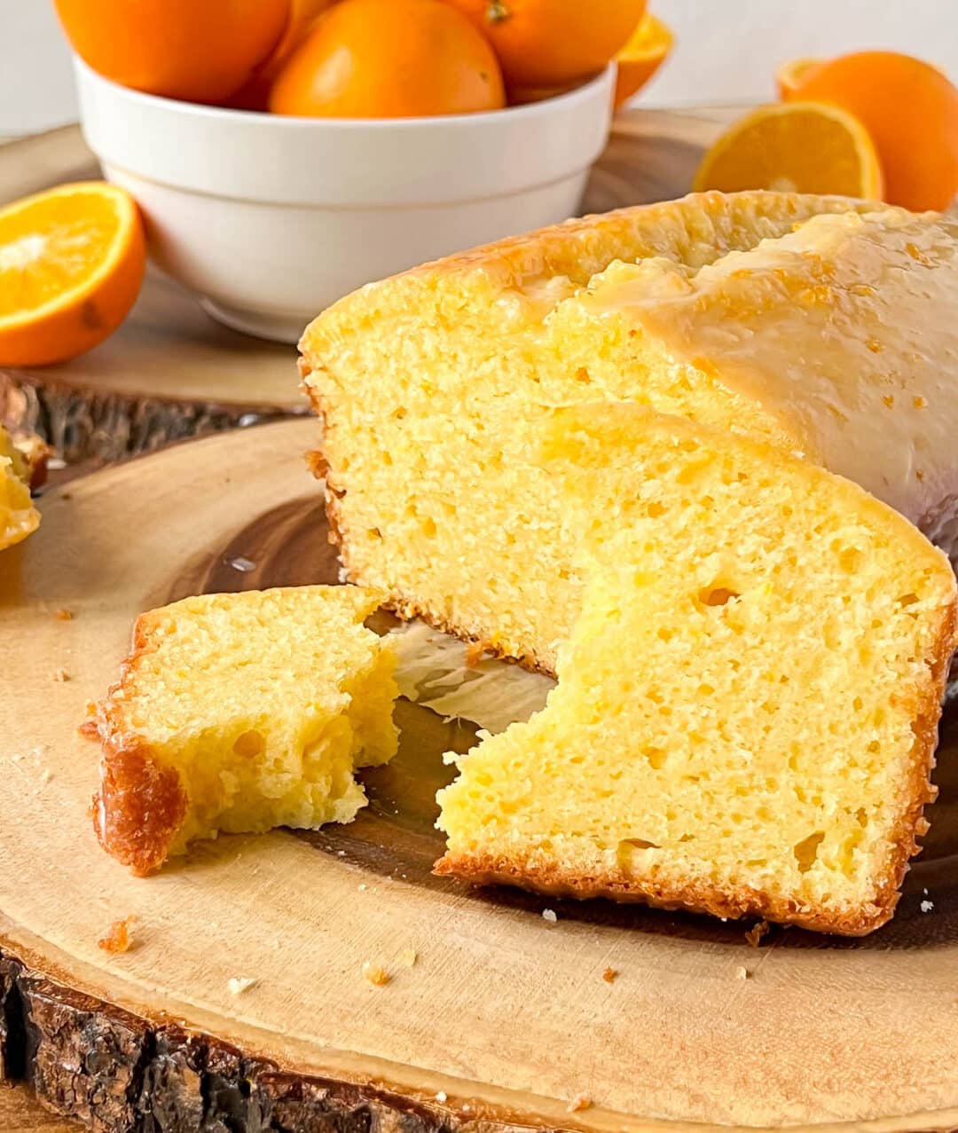 orange loaf cake on a wooden board, with oranges in the back