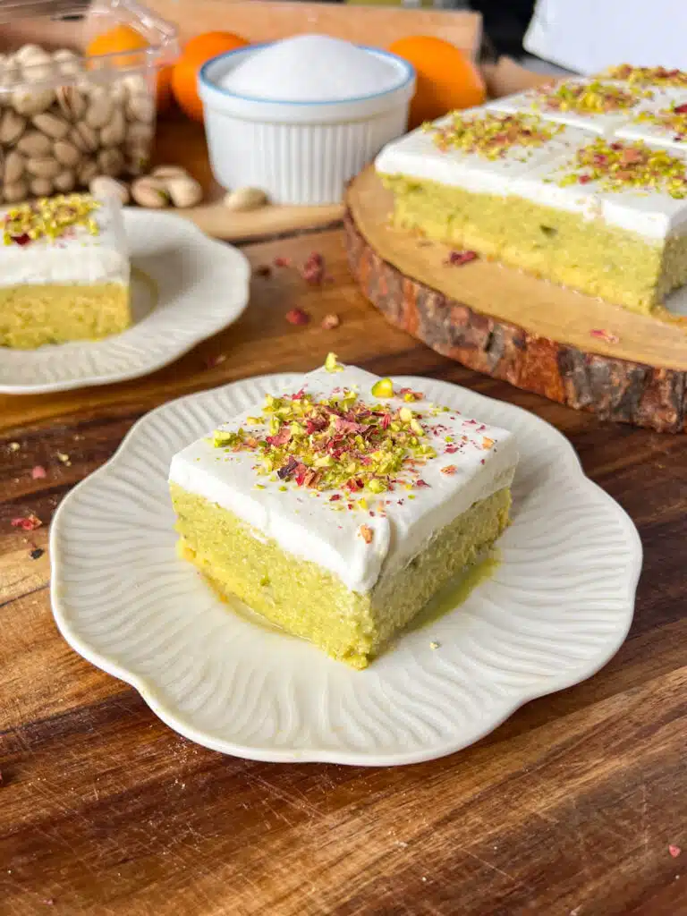 slice of green pistachio tres leches cake (milk cake  in a plate. 