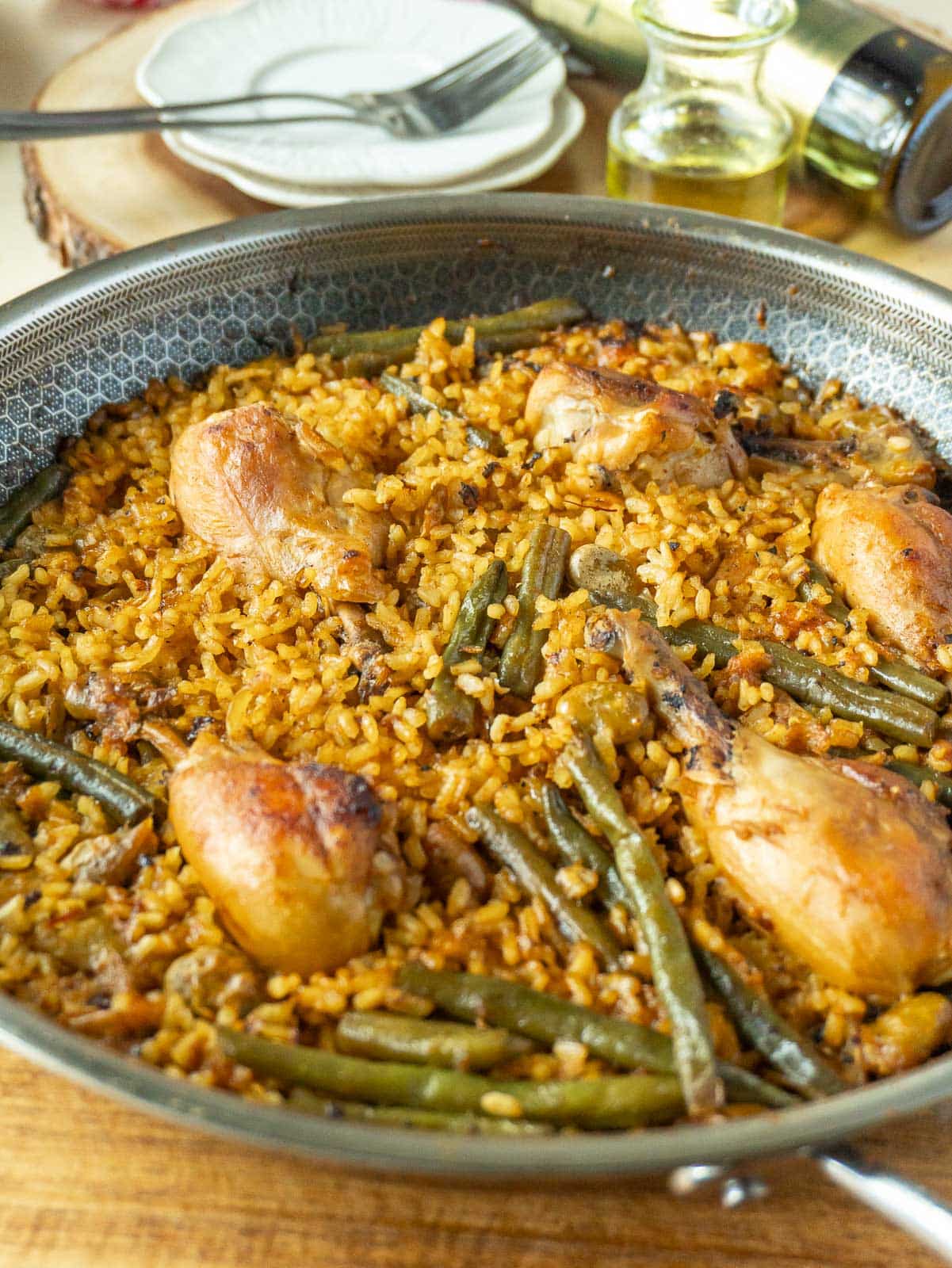 Paella valenciana (chicken paella) in a pan on a wooden cutting board