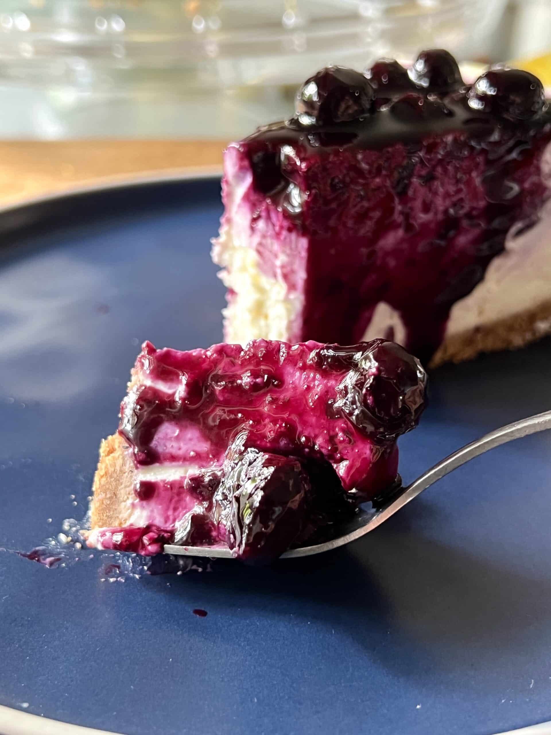 blueberry lemon cheesecake on a plate with a chunk on a fork