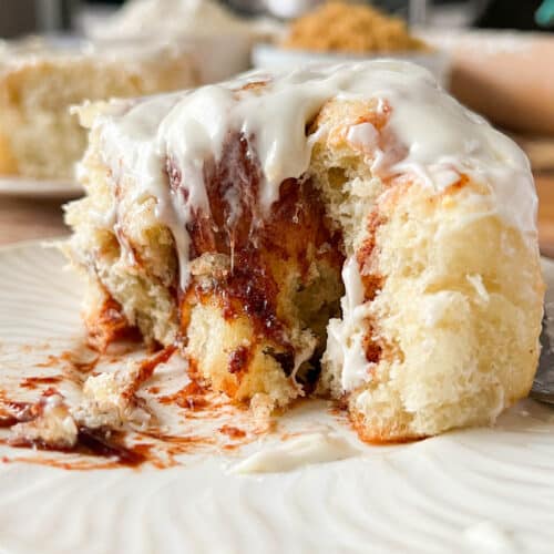 a gooey cinnamon roll cut into on a white plate