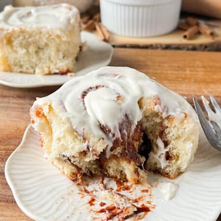 a gooey cinnamon roll cut into on a white plate