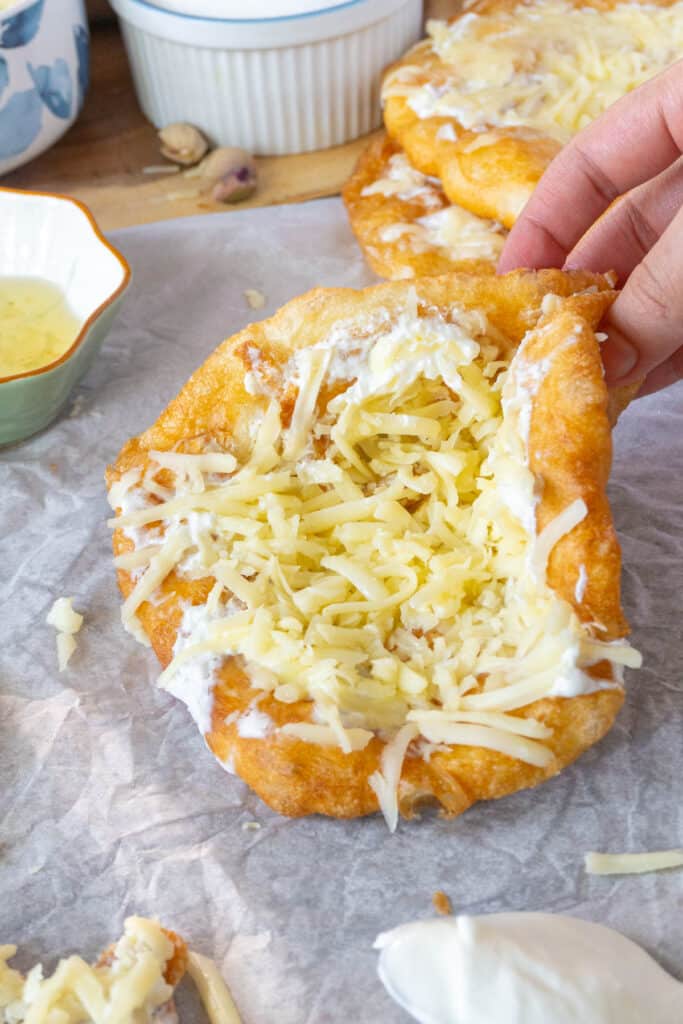 holding a langos (hungarian fried flatbread) with cheese