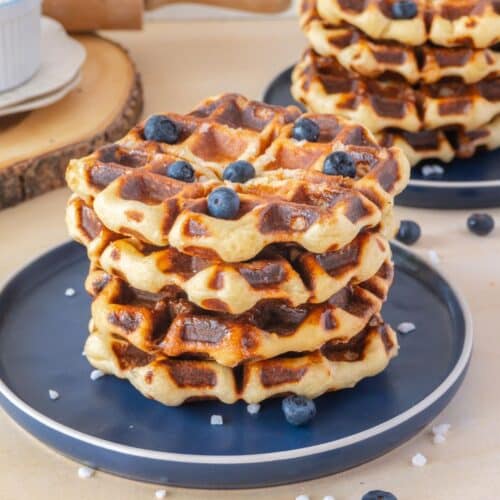 stack of liege waffles on a blue plate with a few blueberries on top