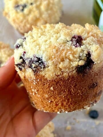 a hand holding a blueberry muffin