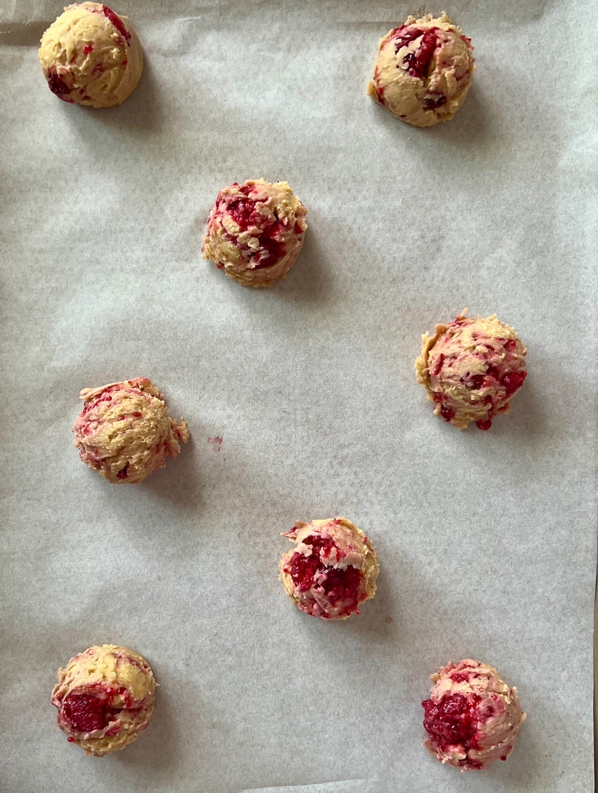 8 vanilla raspberry cookie balls on a baking tray 