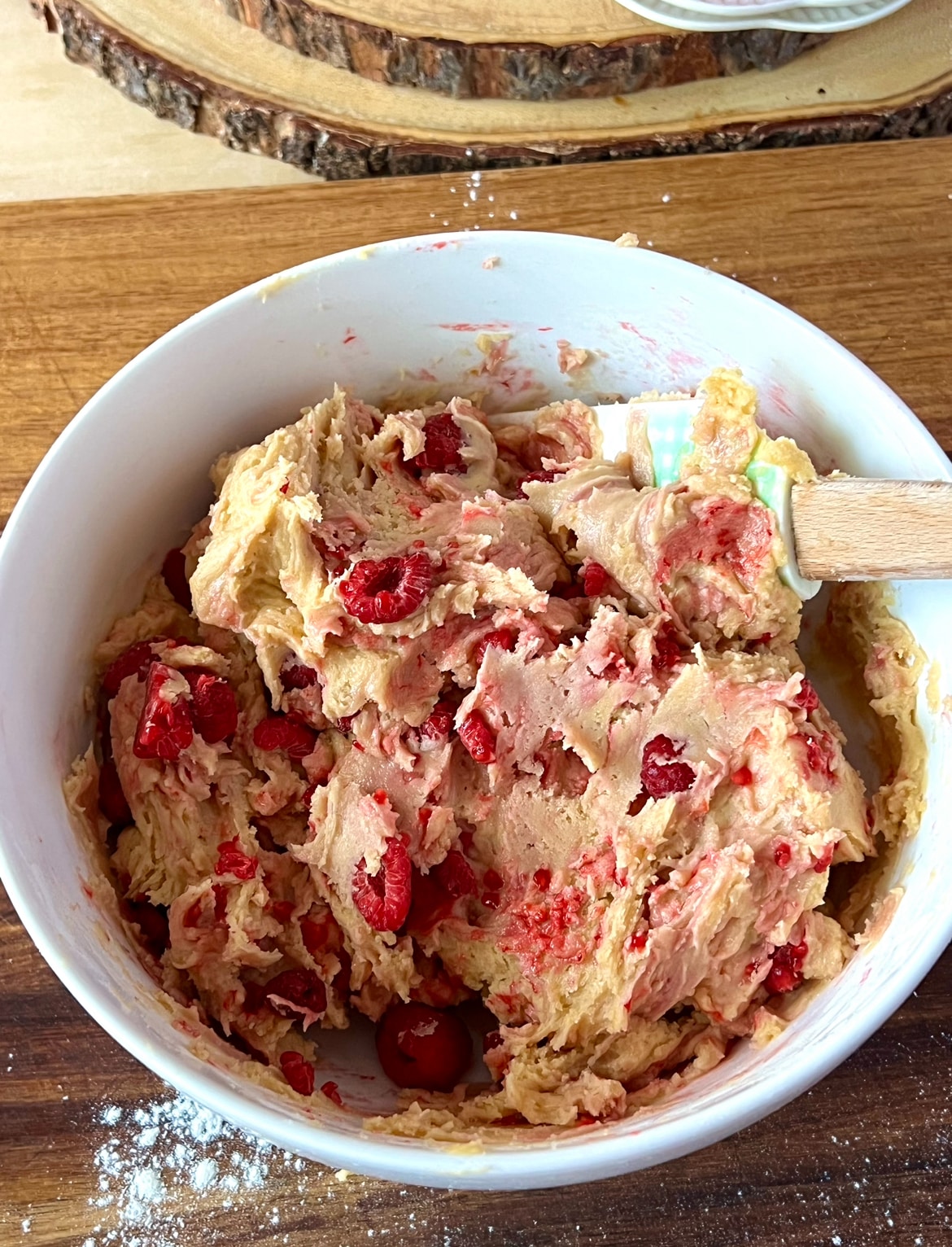 A bowl with vanilla raspberry cookie batter with raspberries mixed in