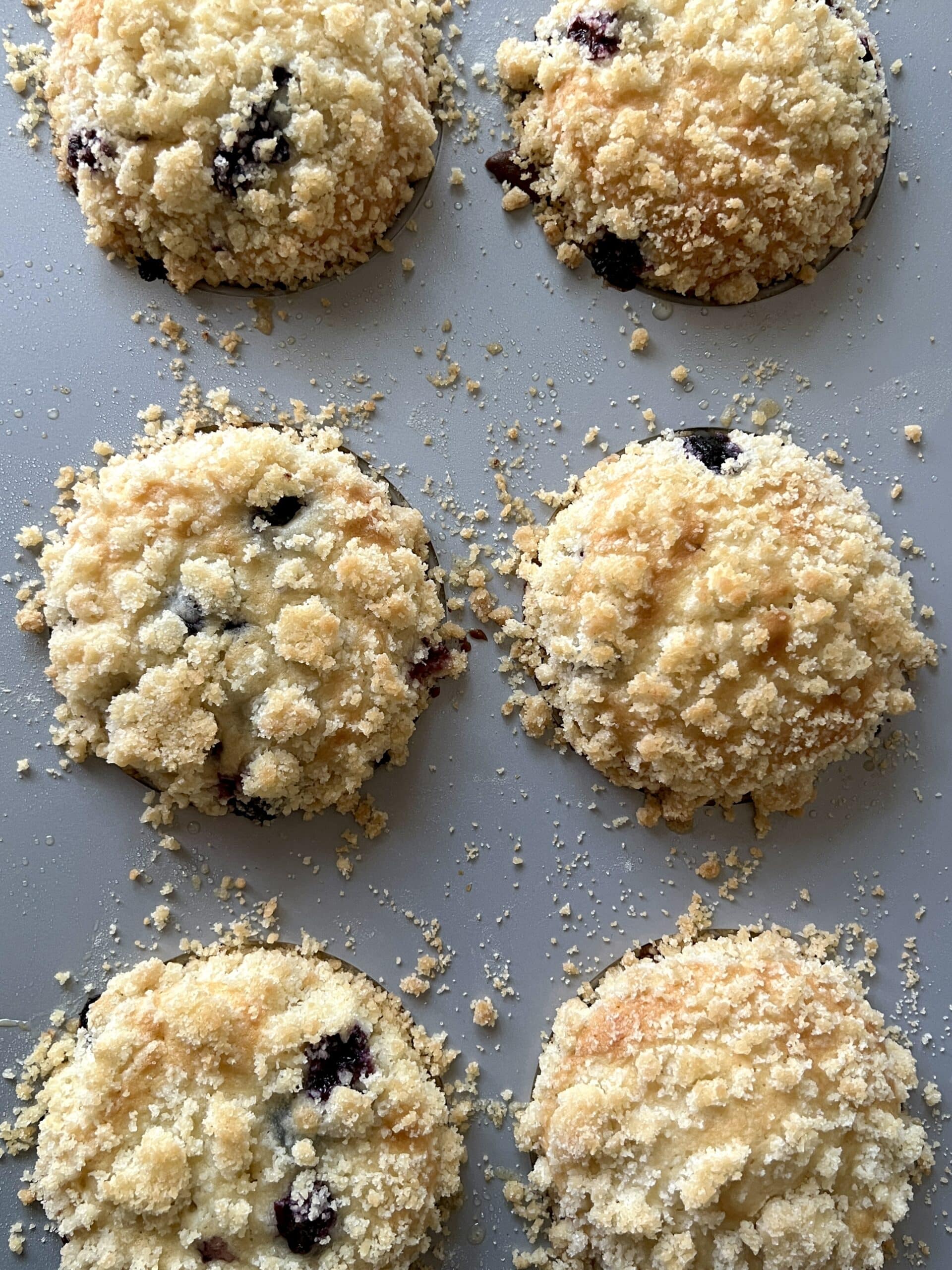 blueberry muffins with crumble in a muffin pan