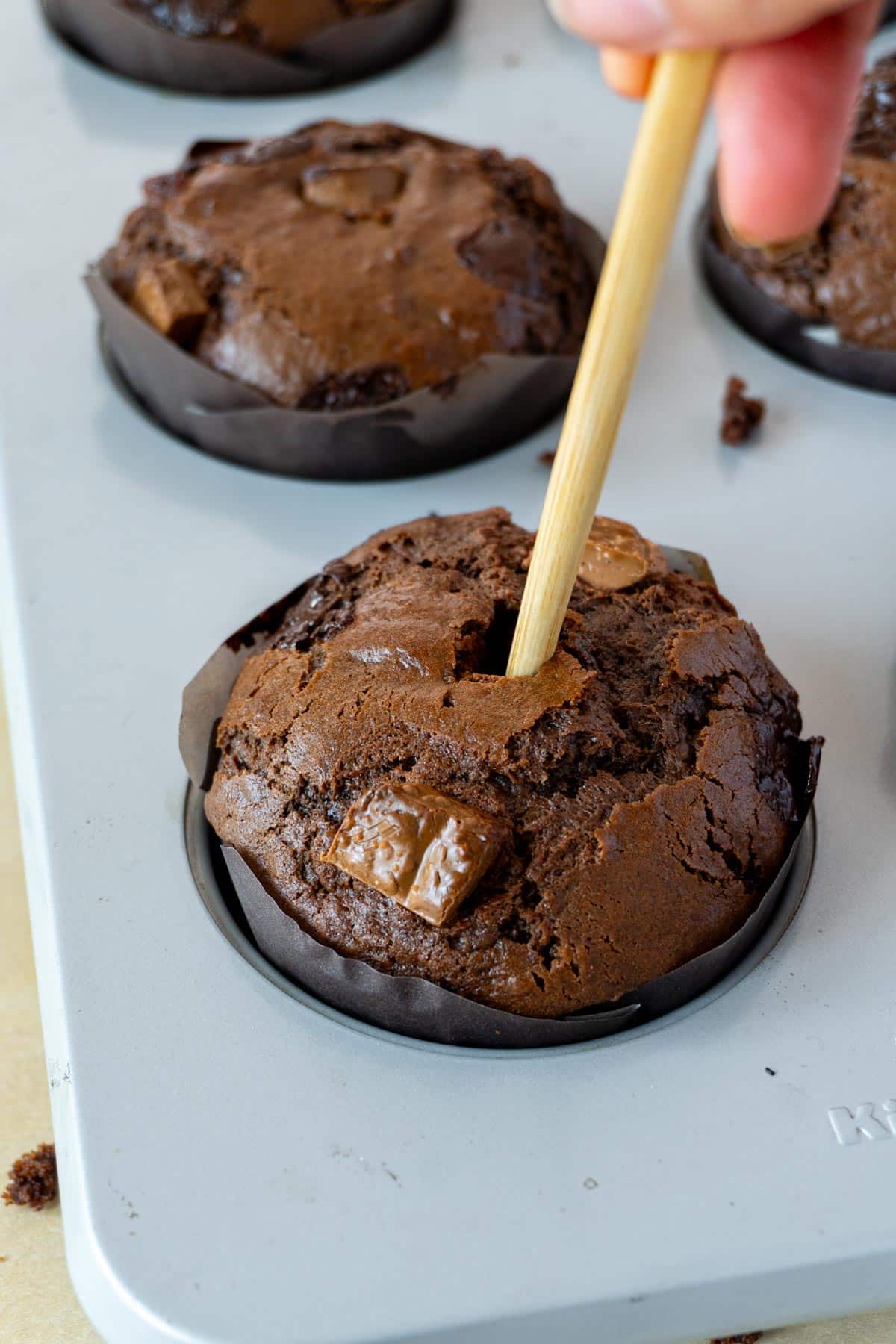 a chopstick making a hole in a chocolate muffin