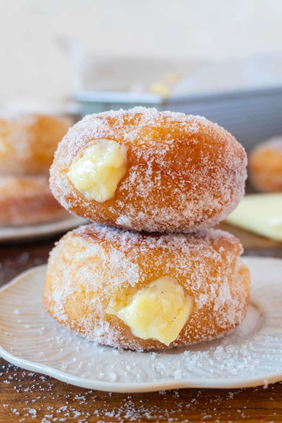 2 bomboloni or italian donuts stacked on a white plate