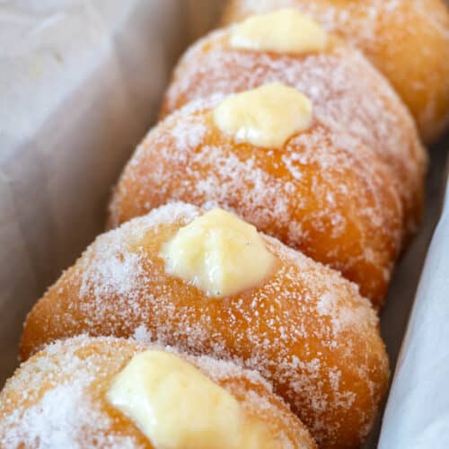 bomboloni or italian donuts lined up in a pan