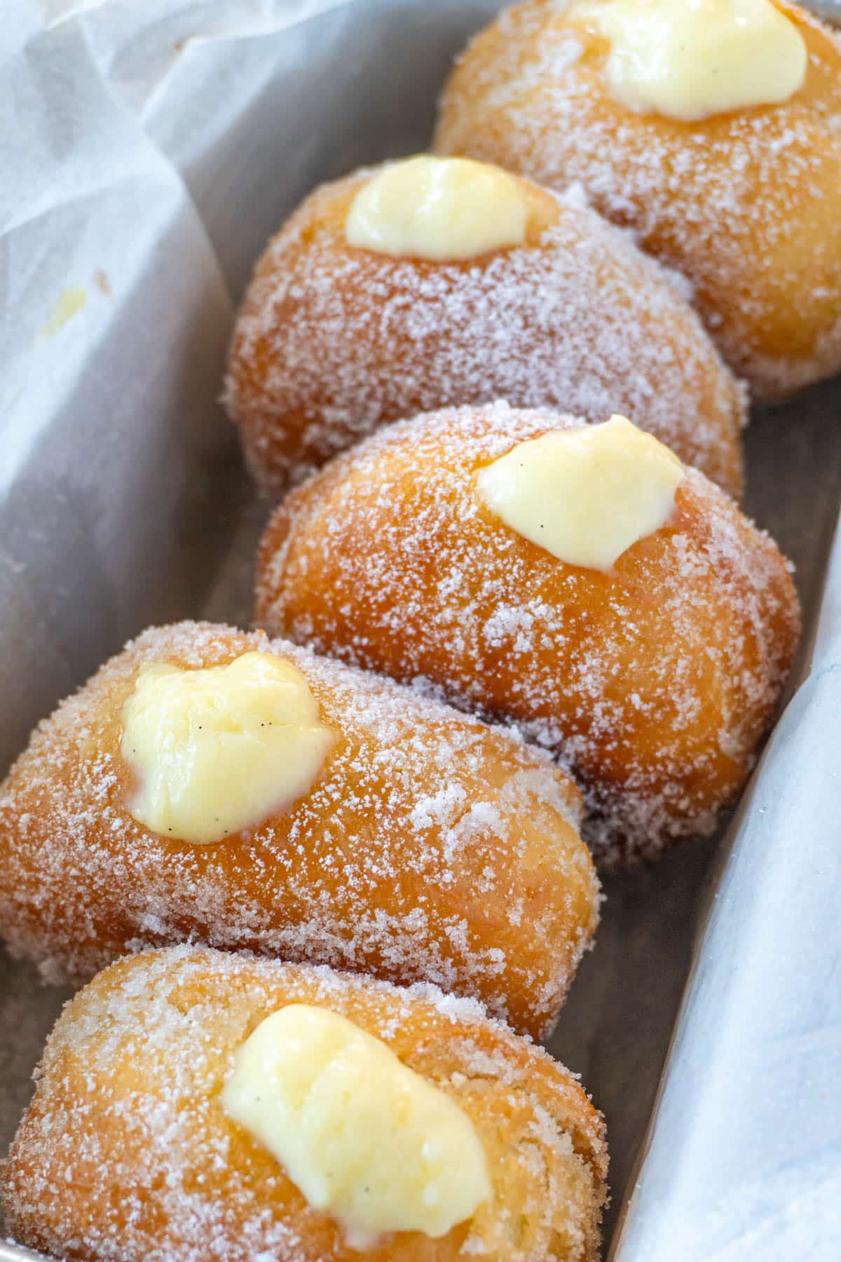 bomboloni or italian donuts lined up in a pan