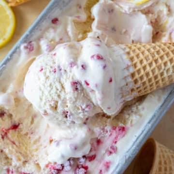 lemon raspberry ice cream in a cone resting in the container of ice cream