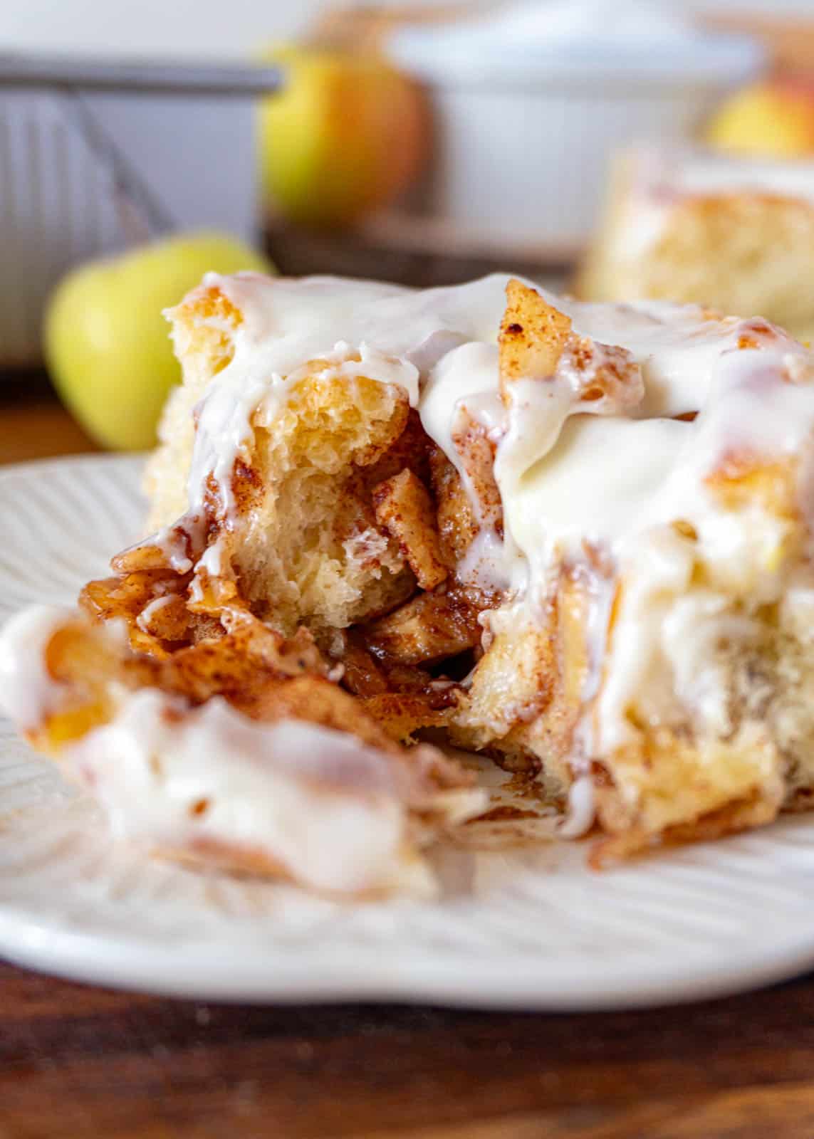 A cut apple pie cinnamon roll, on a white plate