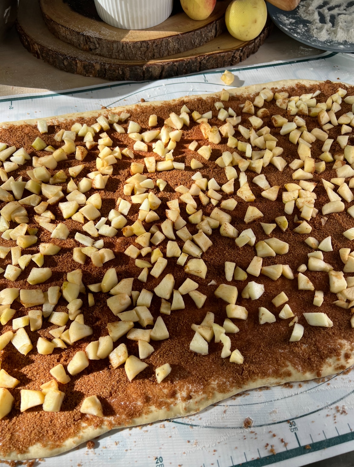 dough rolled out and covered with cinnamon spiced sugar and chopped apples