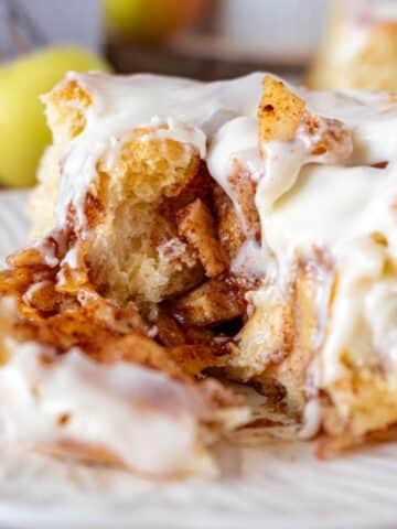 A cut apple pie cinnamon roll, on a white plate