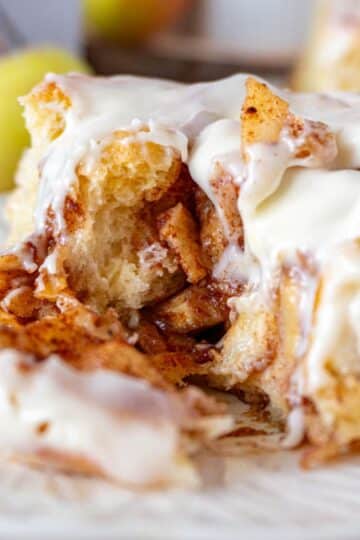 A cut apple pie cinnamon roll, on a white plate