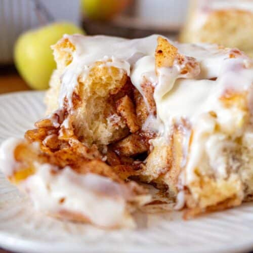 A cut apple pie cinnamon roll, on a white plate