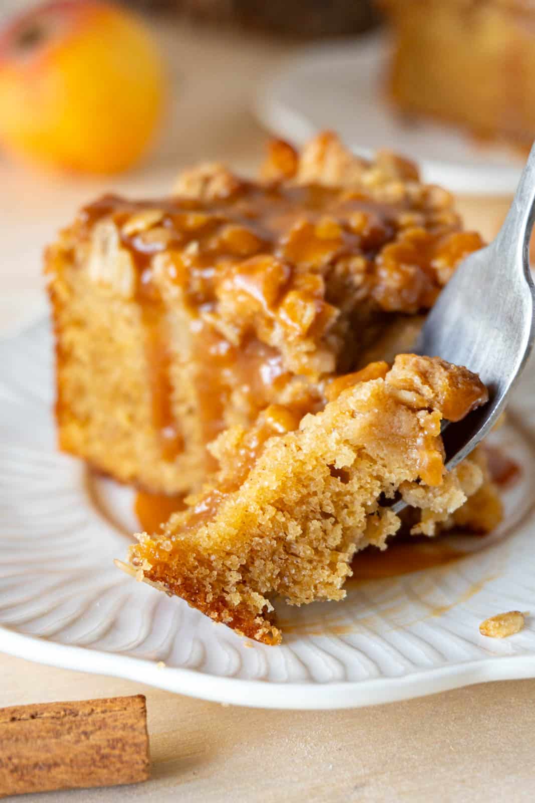 A slice of apple crumble cake, with a fork, on a white plate