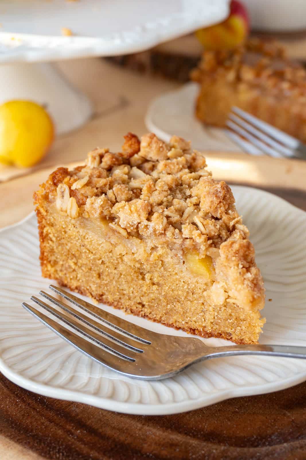 A slice of apple crumble cake, with a fork, on a white plate