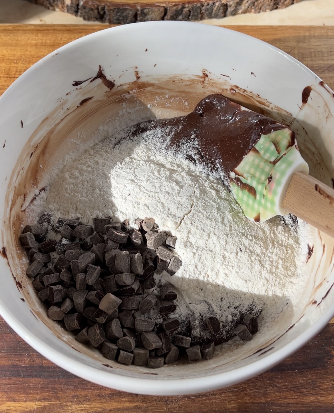 A bowl with brownie cookie batter, flour and chocolate chips