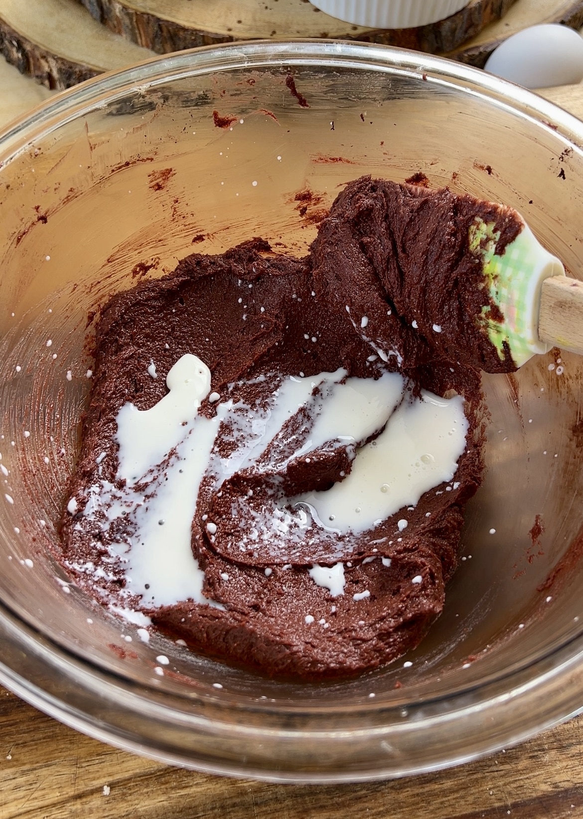 Red velvet cookie batter in a bowl with milk added in