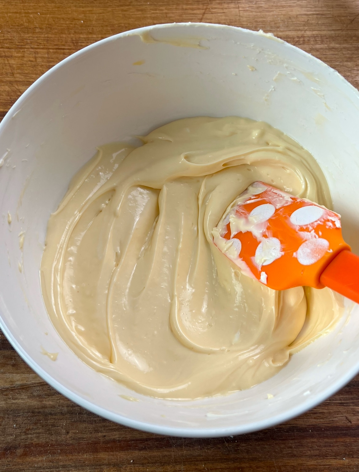 Cream cheese mixture in a white bowl with an orange spatula