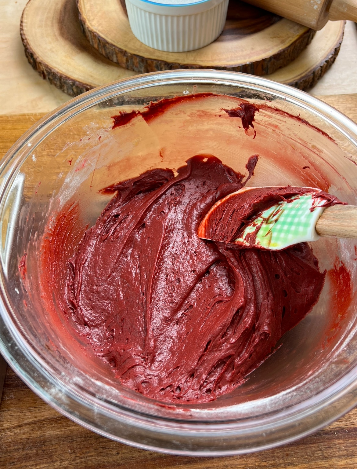 red velvet brownie mixture in a glass bowl, witha green spatula