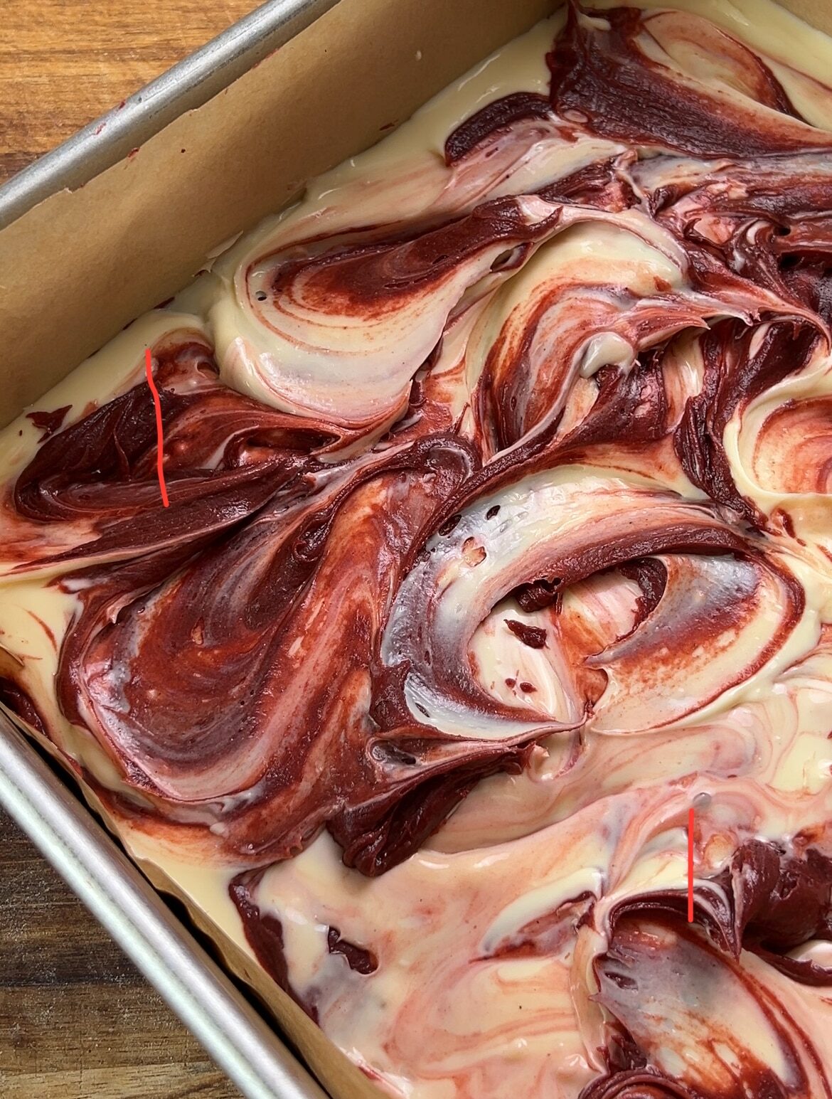 swirled red velvet brownie cheesecake mixture in a pan