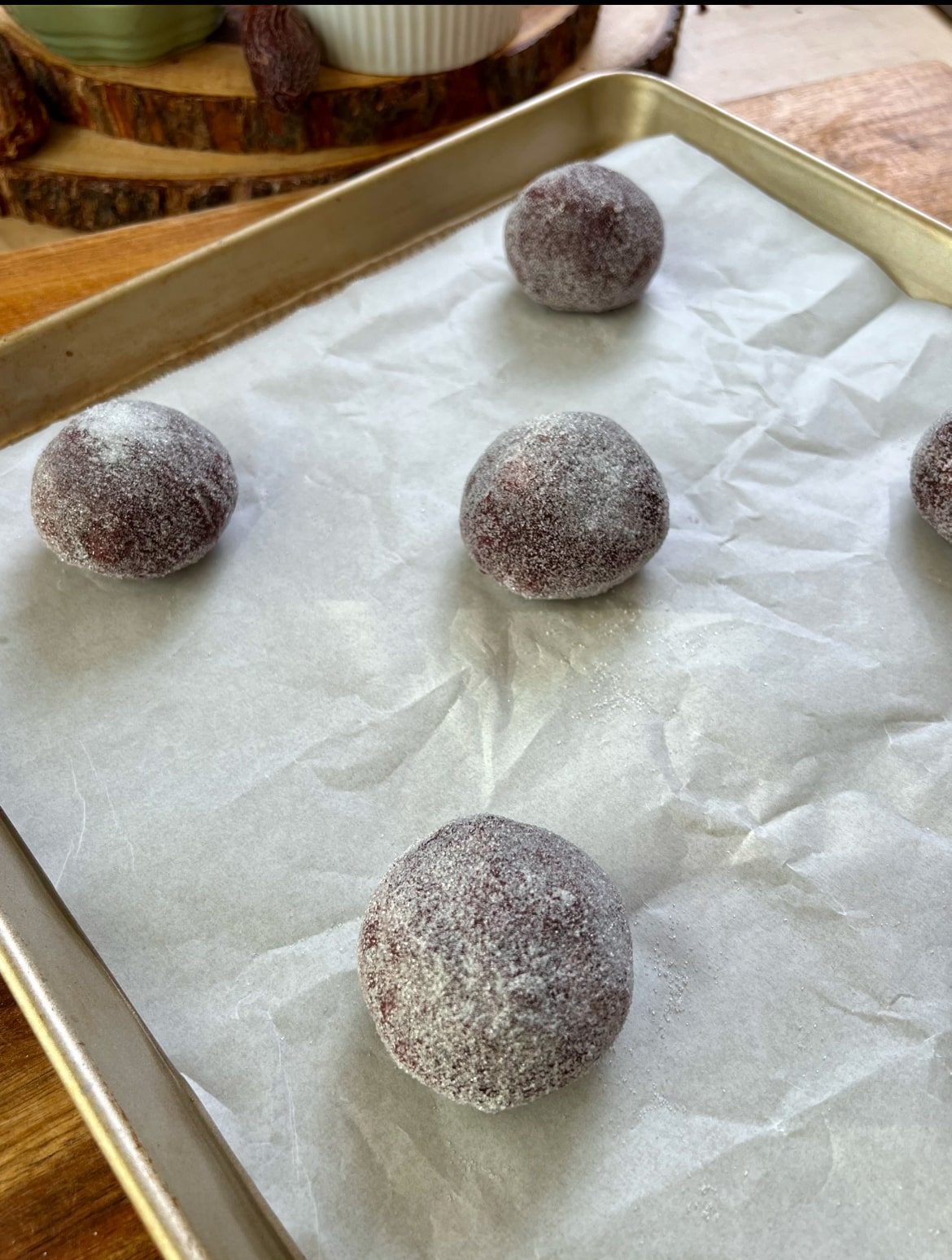 5 Cookie balls covered in sugar on a baking tray