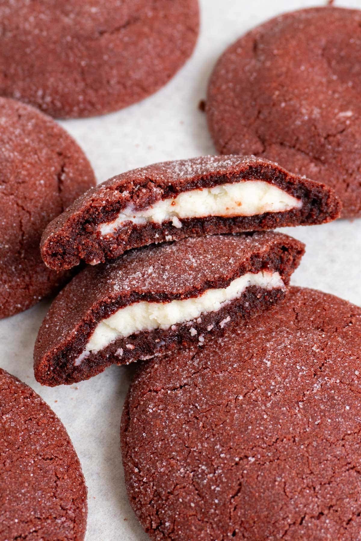 stuffed red velvet cookie broken in half and surrounded by 5 more cookies