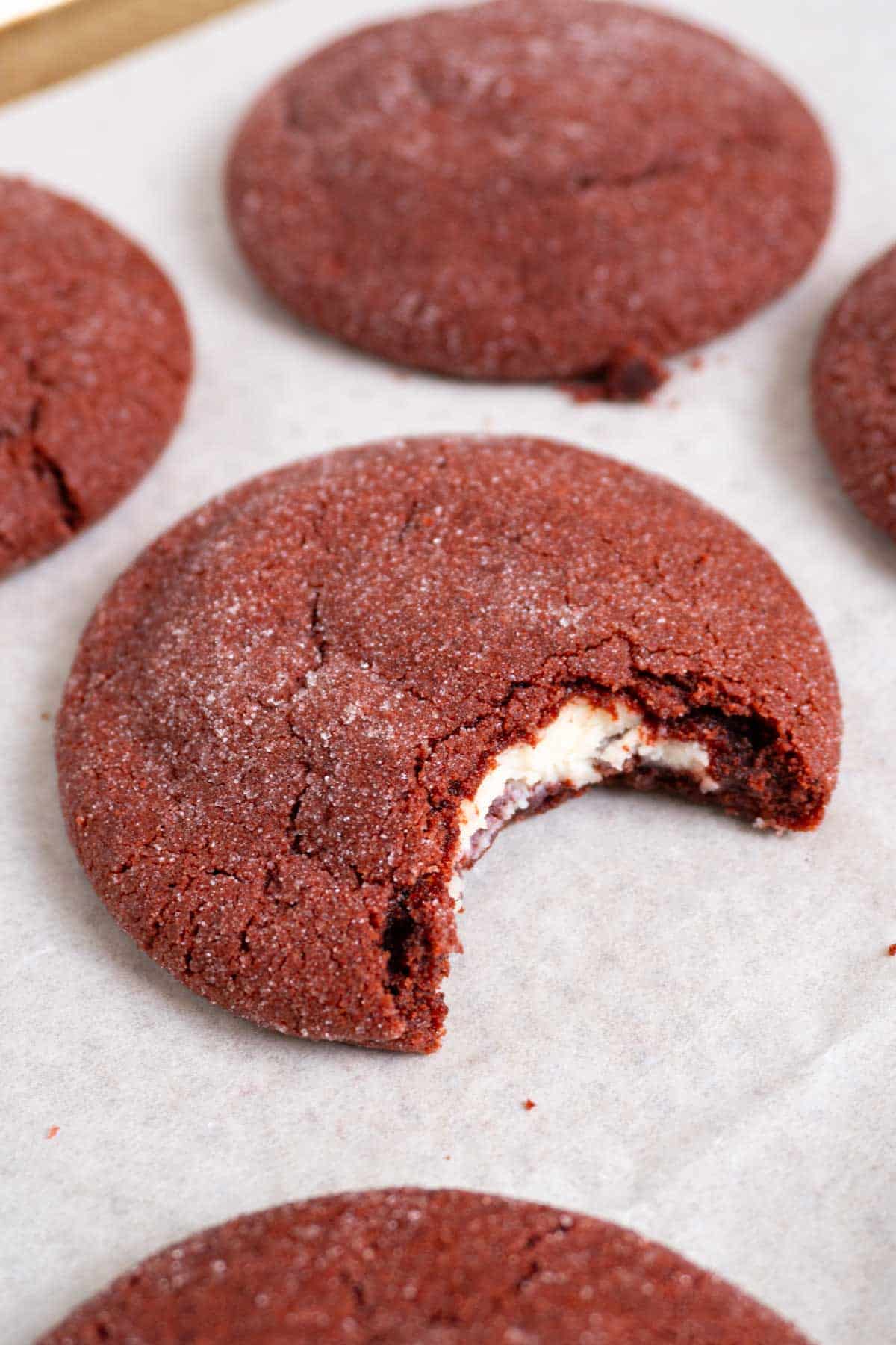 red velvet cookie, on a white surface. The cookie has a bite taken out of it