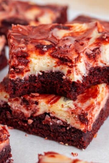 2 red velvet cheesecake brownies stacked, with the top one bitten