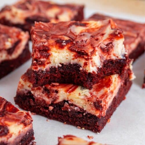 2 red velvet cheesecake brownies stacked, with the top one bitten