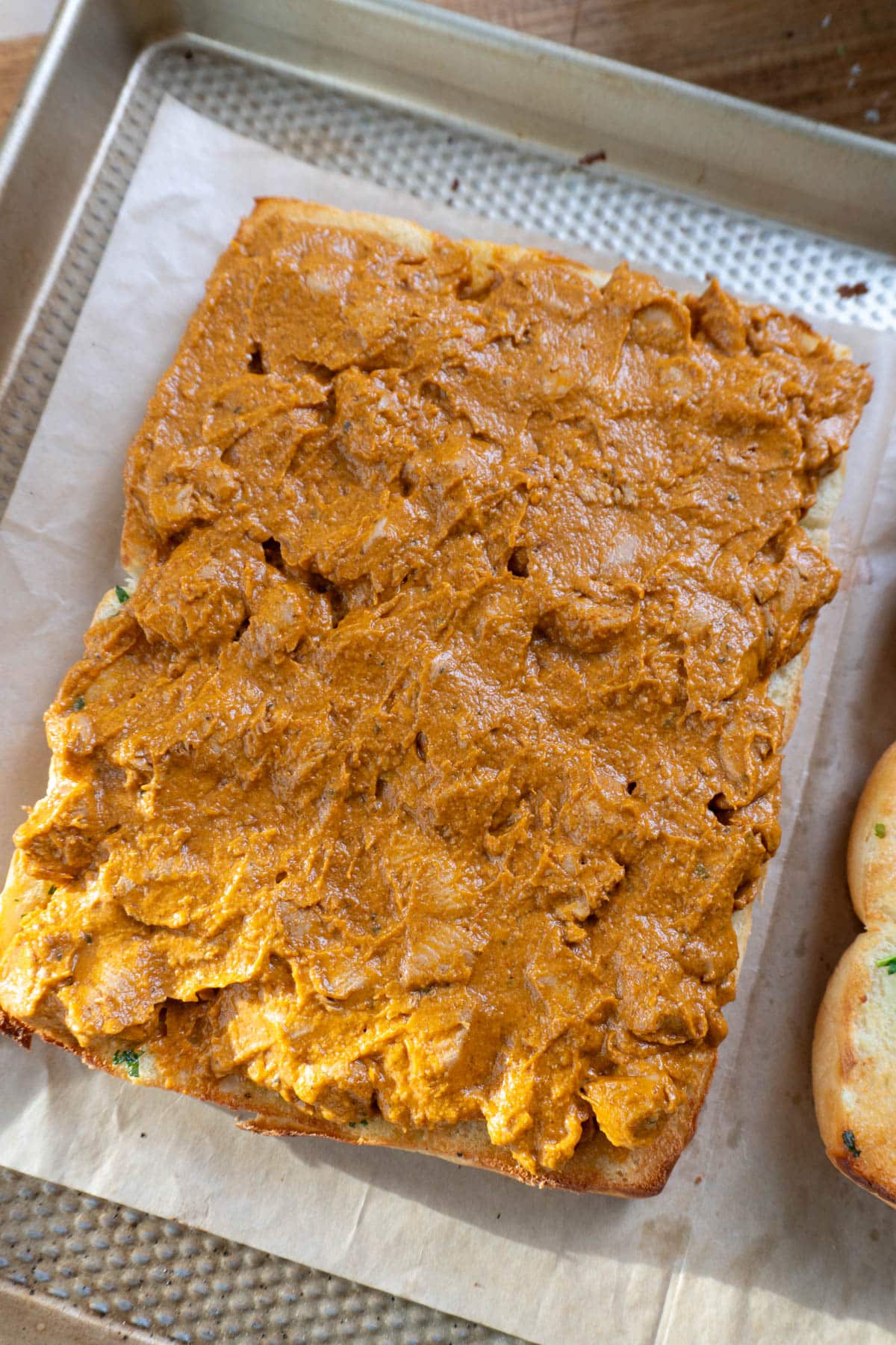 Butter chicken spread on a cut half of hawaiian rolls