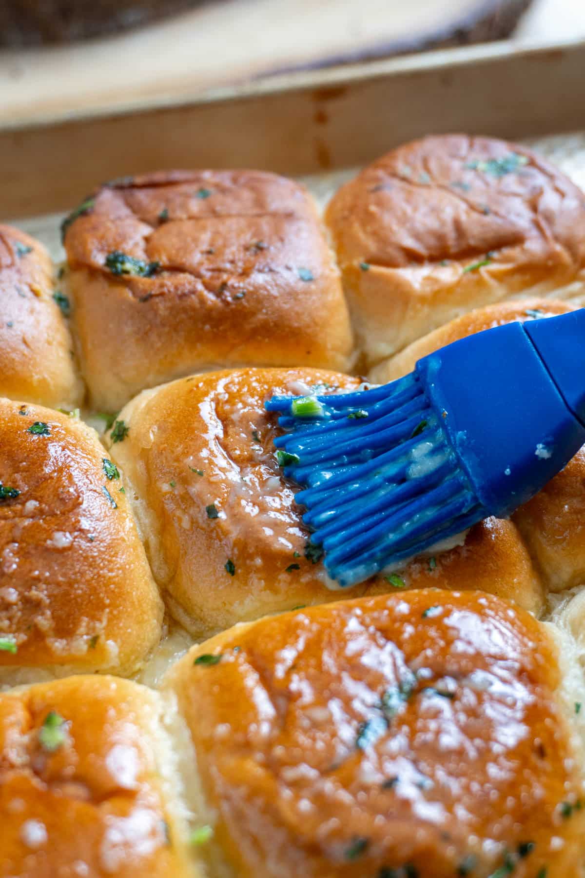 garlic butter being brushed onto butter chicken rolls
