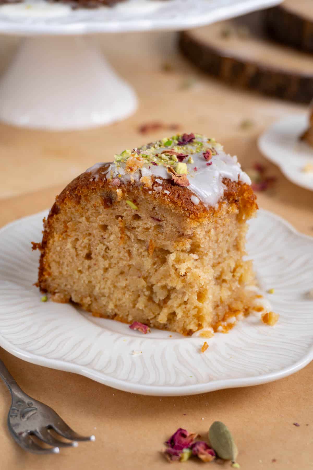 A slice of gulab jamun cake on a white plate, bitten into