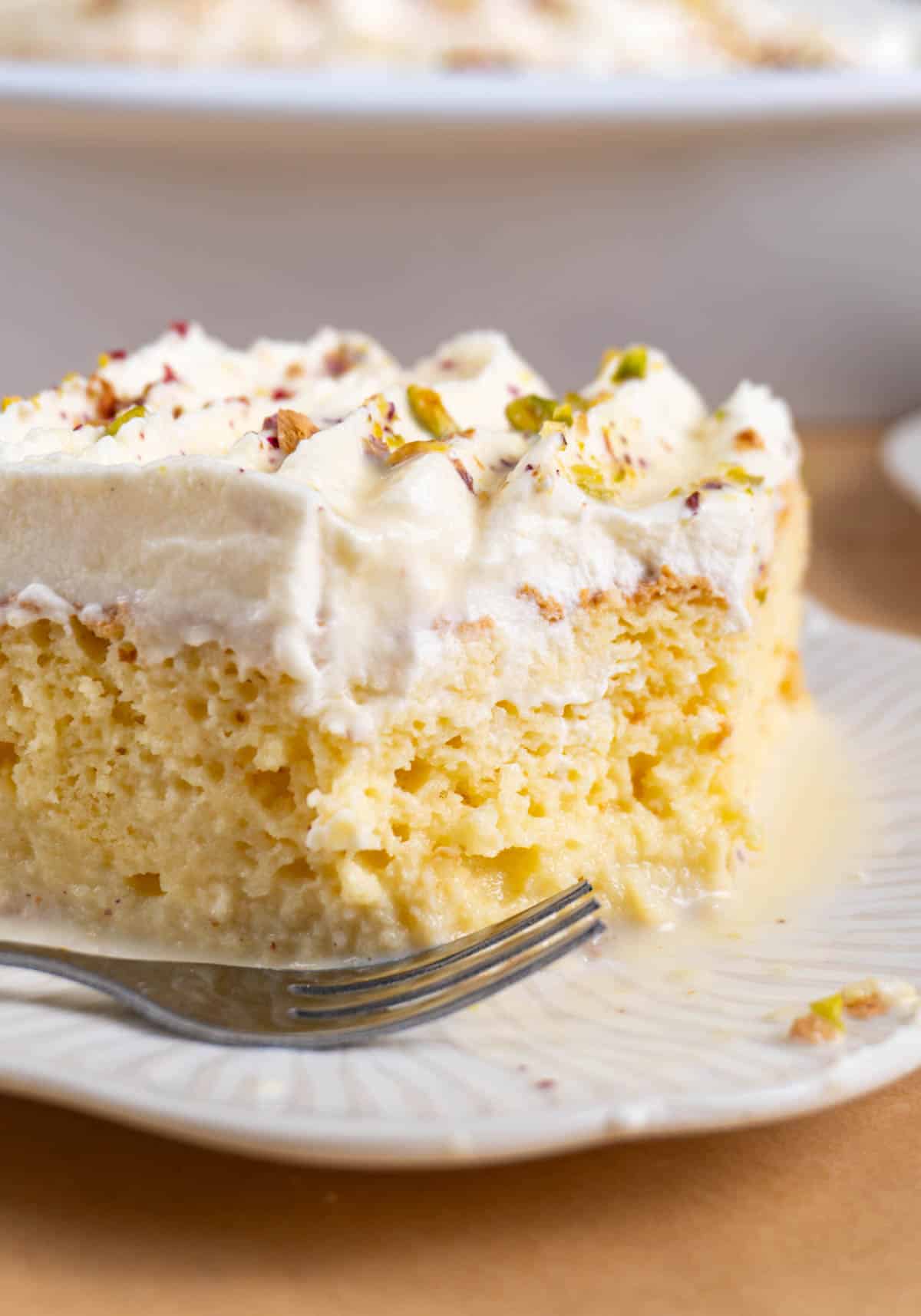 a slice of rasmalai tres leches on a white plate.