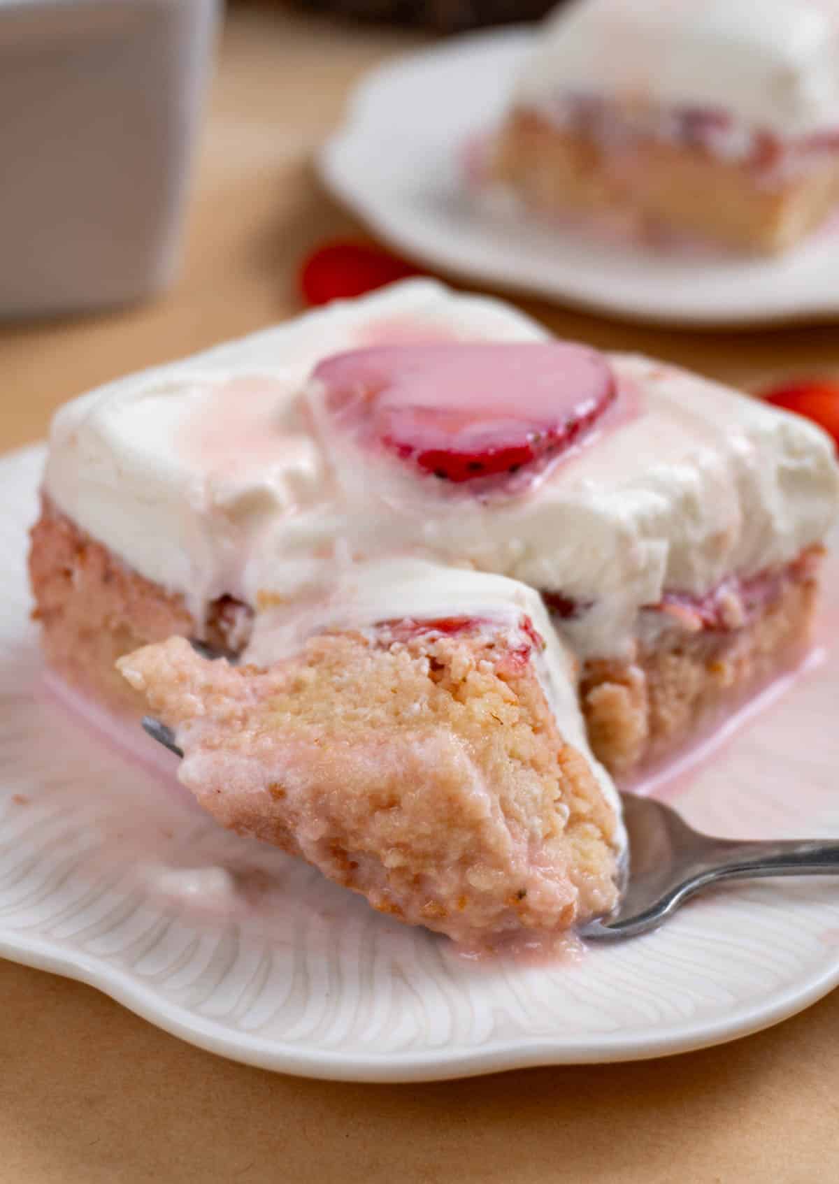 fork cutting into a slice of strawberry tres leches