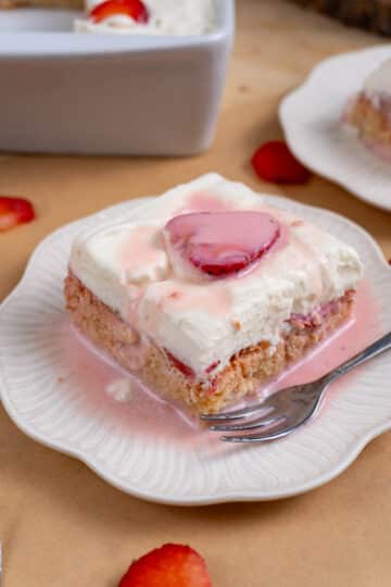 a pink strawberry tres leches cake on a white plate