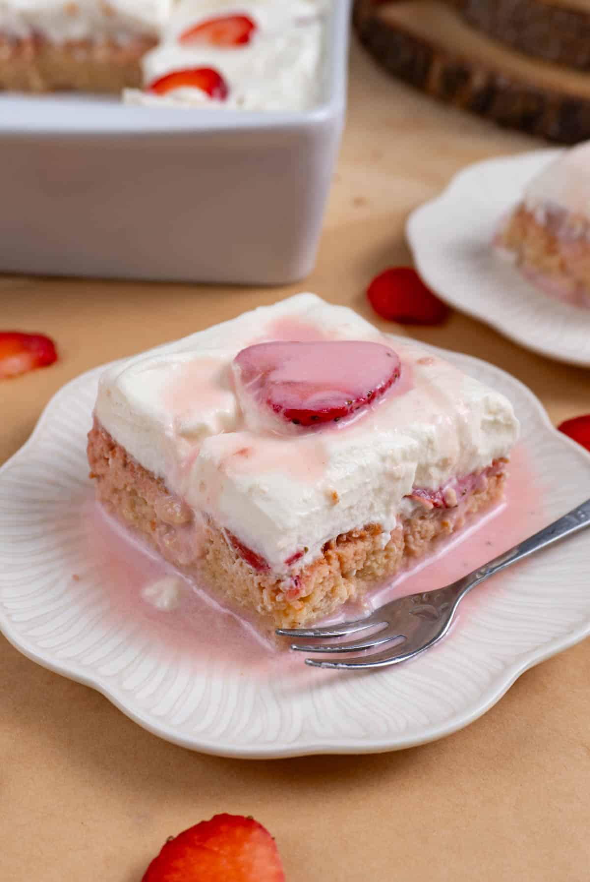 a pink strawberry tres leches cake on a white plate