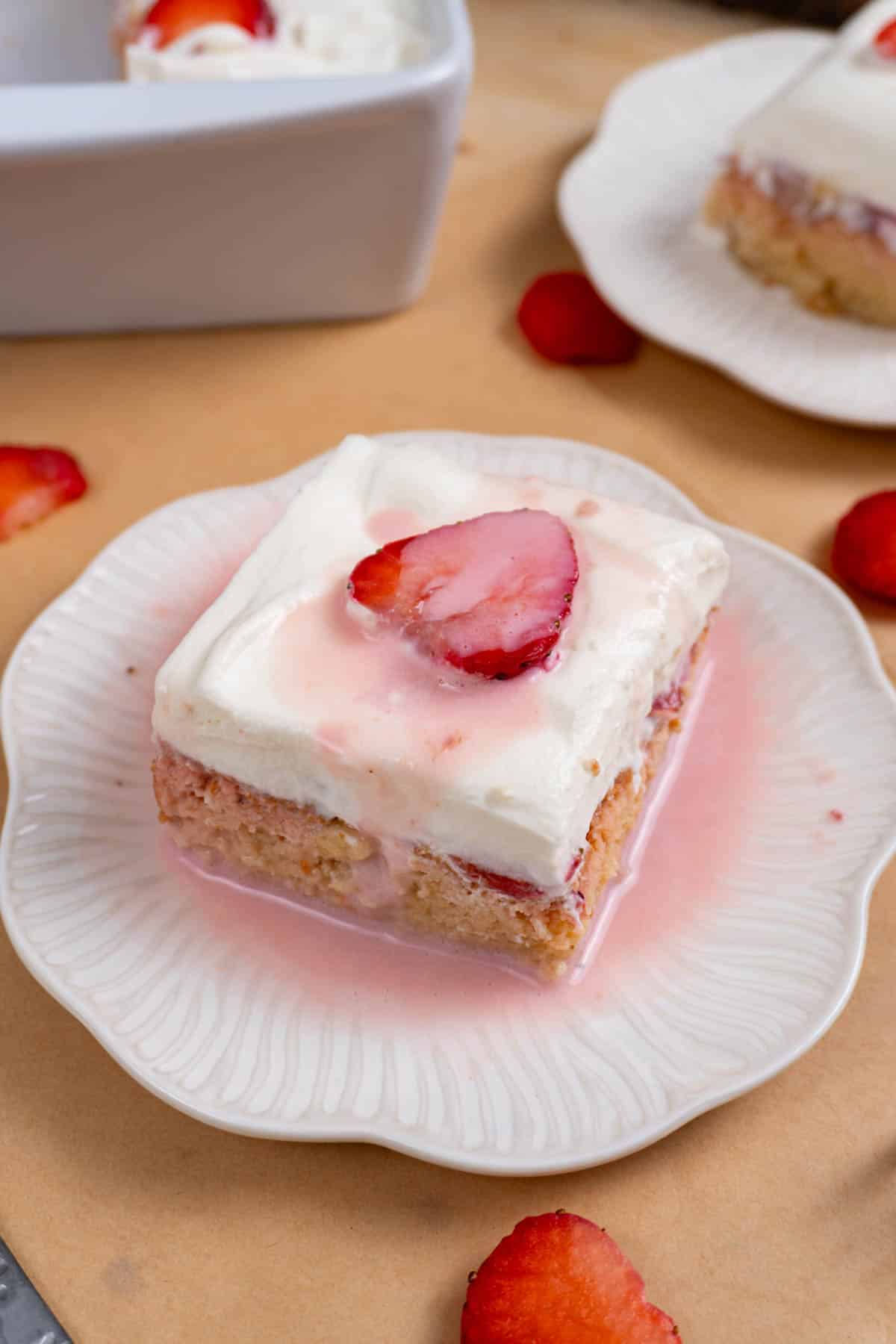 a pink strawberry tres leches cake on a white plate