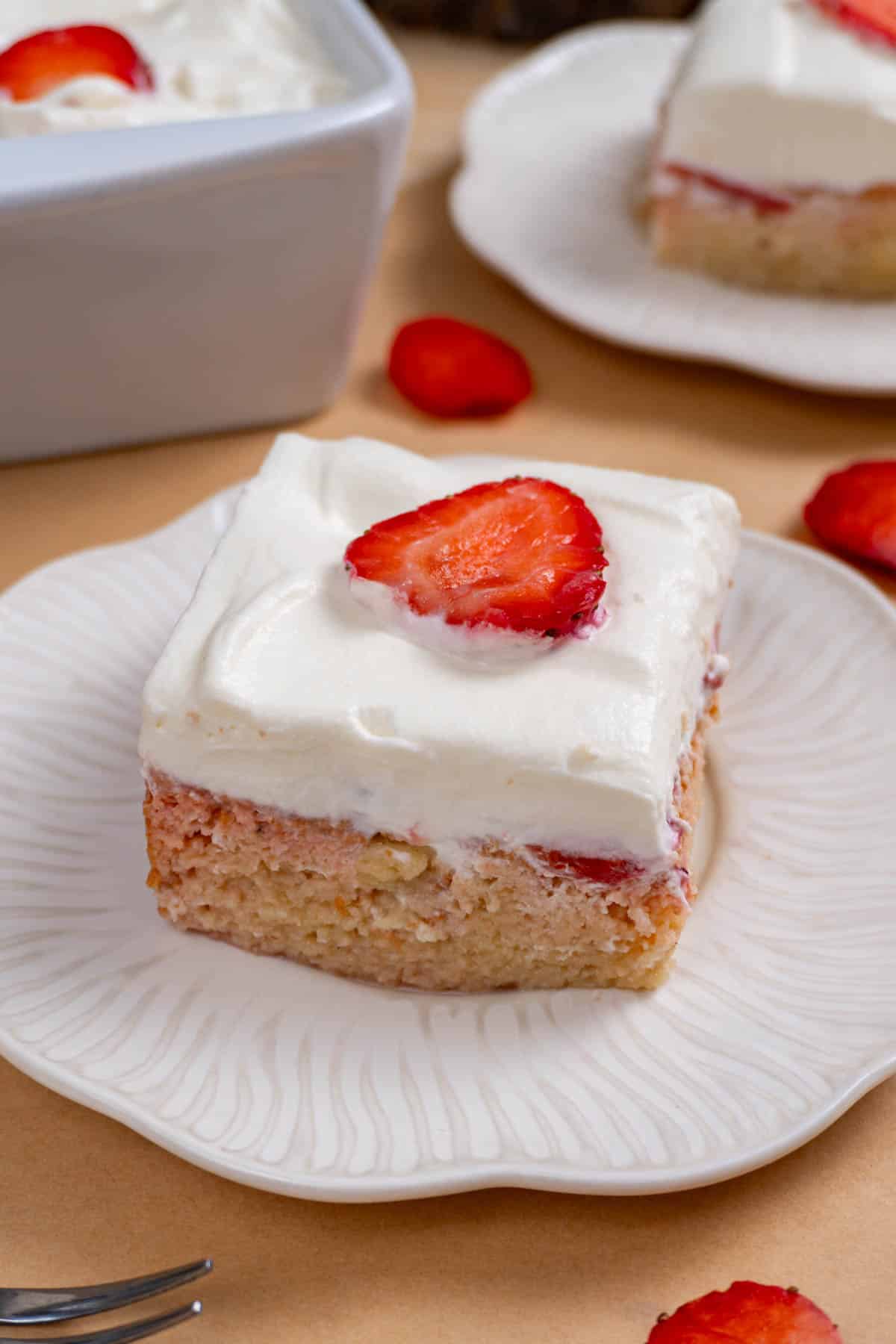 a slice of strawberry tres leches on a white plate.
